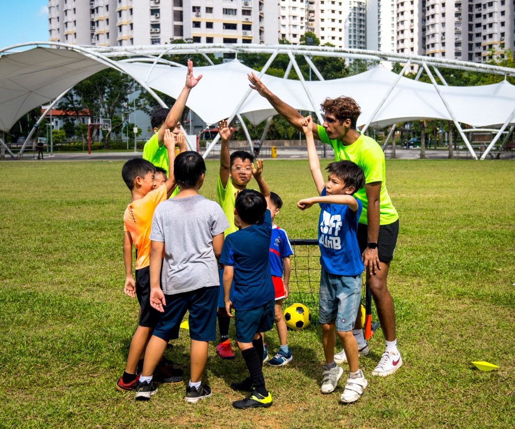 kids and football coaches doing a team cheer