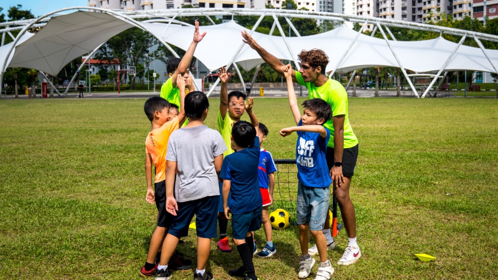 kids and football coaches doing a team cheer