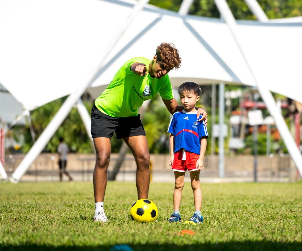 football coach guiding kids on where to kick the ball towards