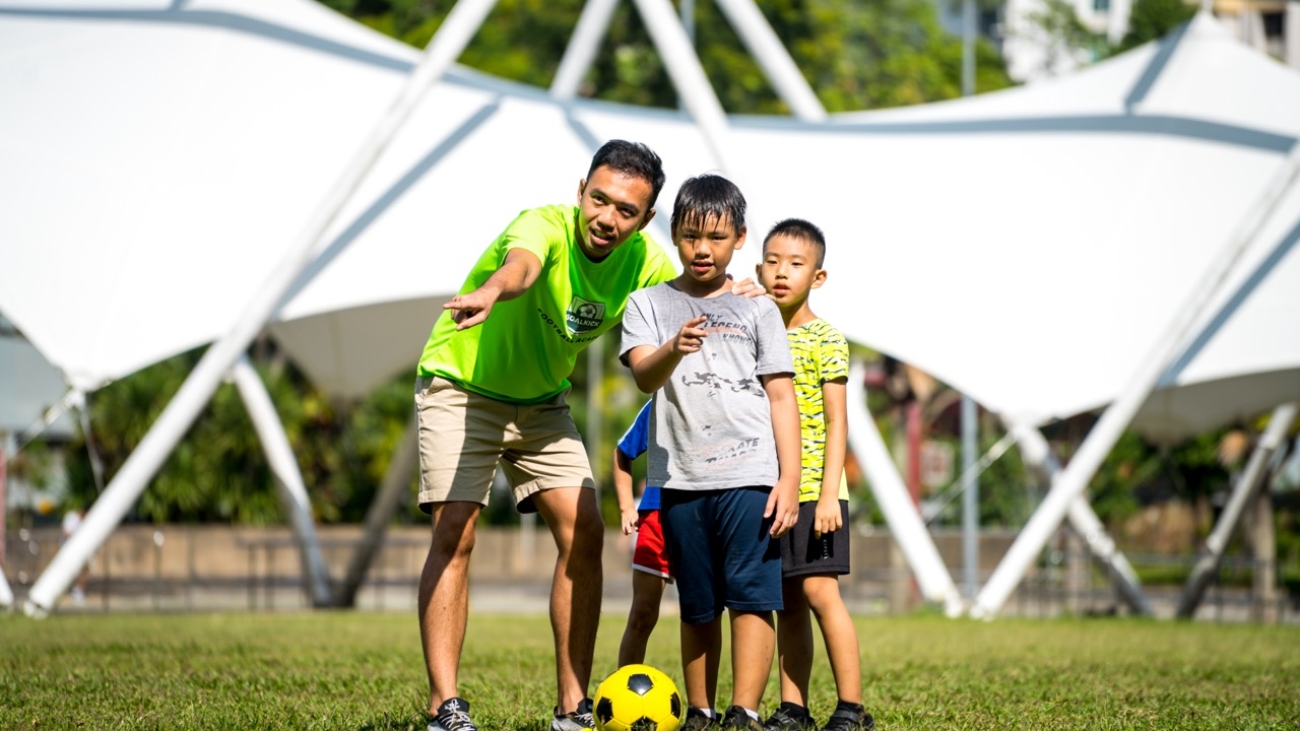 football coach guiding kids on where to kick the ball towards